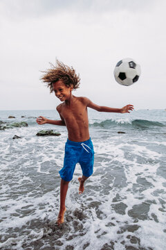 Boy playing with a football on the beach