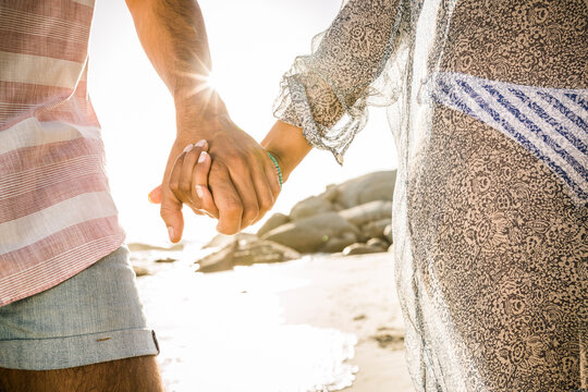Close-up of couple holding hands on the beach