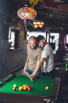 Gay couple playing billiards together, having fun