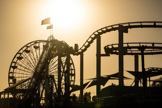 USA, California, Santa Monica, Silhouettes of Ferris wheel and rollercoaster of Santa Monica Pier at sunset