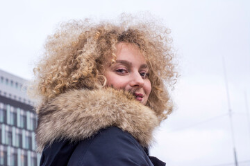 Portrait of smiling blond woman with ringlets wearing fur collar