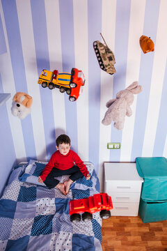 Little boy meditating on his bed with toys flying over his head