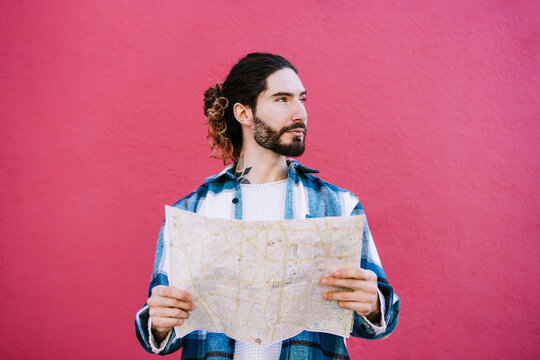 Man holding map while standing against red wall