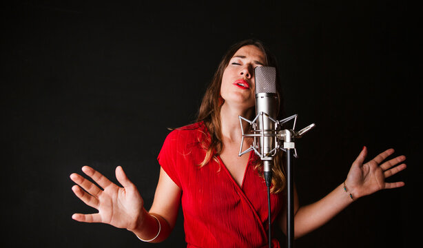 Portrait of female singer with microphone, wearing red dress