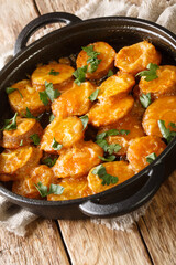 Patatas a la importancia is a traditional Spanish dish made with potato slices that are fried in a batter of flour and eggs close up in the pan on the table. Vertical