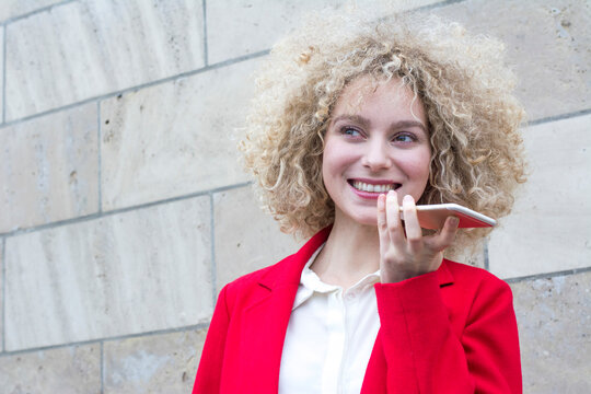 Portrait of smiling blond woman with ringlets talking on the phone