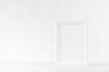 White wood blank rectangle photo frame on soft light white table and plaster wall in modern minimal simple style, copy space. Mockup for design, showing, display, text presentation of portfolio.