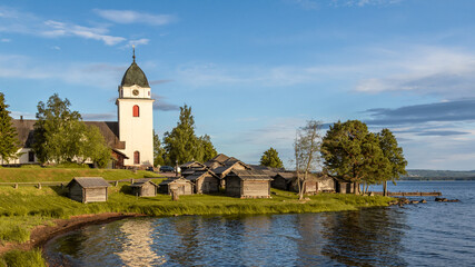 Fototapeta premium church and small wooden cabins on a lakeshore in the Swedish countryside