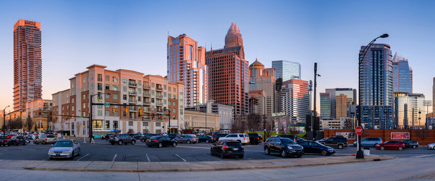 Panoramic view of cars in parking lot by buildings against clear sky during sunset