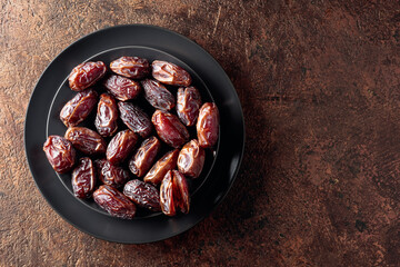 Dried sweet dates on a black plate.
