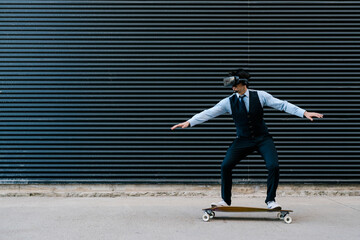 Businessman skateboarding on longboard while watching movie through virtual reality simulator against black wall