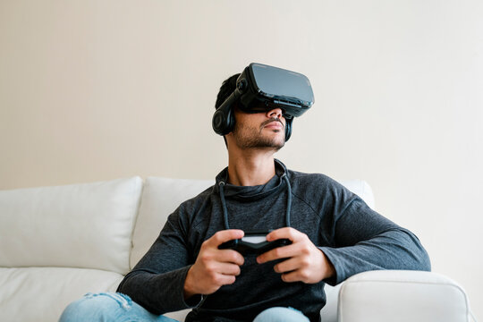Young man playing video game through virtual reality simulator