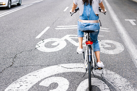 Low section of woman riding bicycle on street in city
