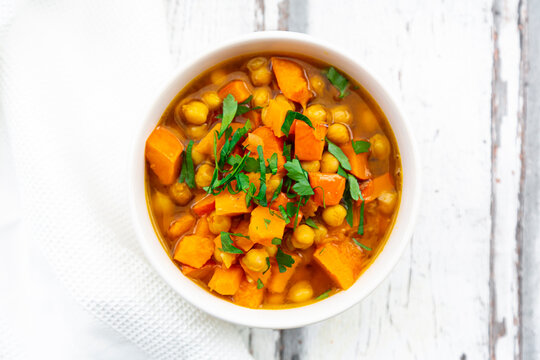 Bowl of oriental pumpkin stew with red kuri squash, roasted turmeric chick-peas and parsley