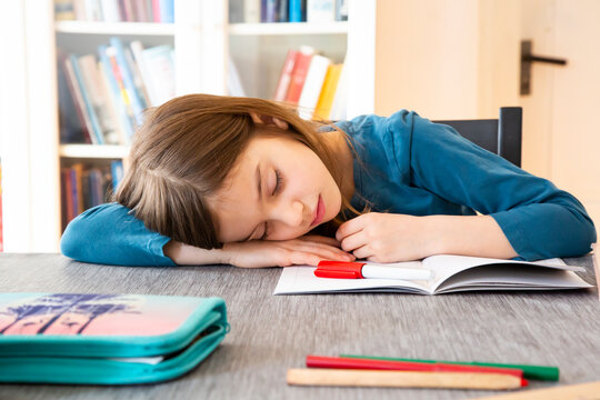 Schoolgirl napping at table with homework