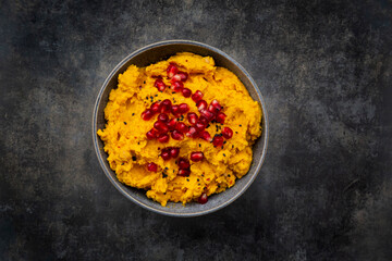 Bowl of pumpkin hummus with black sesame and pomegranate seeds