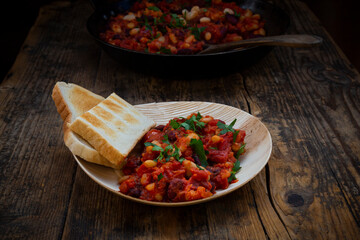 Vegan baked kidney beans, white beans, tomatoes and parsleyÔøΩon environmentally friendly plate made from palm leaves