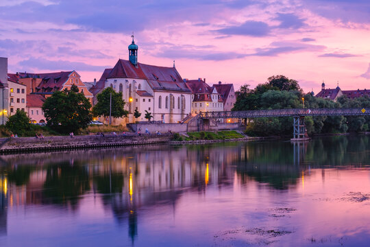St. Oswald Church with Eiserner Steg bridge across Danube River in Regensburg during sunset, Upper Palatinate, Bavaria, Germany