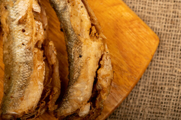 Small fried fish on a wooden board, close-up, selective focus.