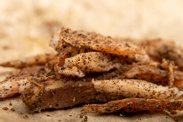 thinly sliced homemade lard with pepper on white oiled paper, close-up, selective focus.
