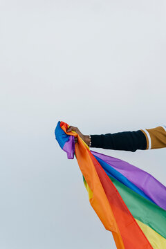 African man holding LGTBQI flag against white wall