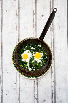 Green Shakshouka with baby spinach, chard, spring onions and basil in a pan