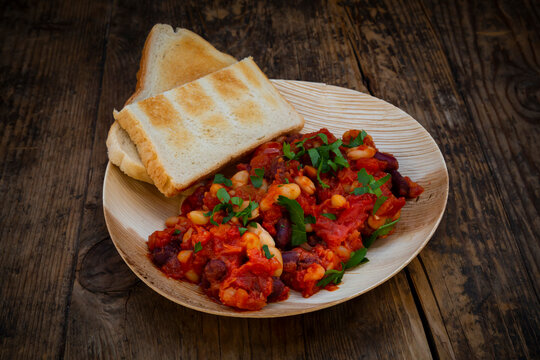 Vegan baked kidney beans, white beans, tomatoes and parsleyÔøΩon environmentally friendly plate made from palm leaves