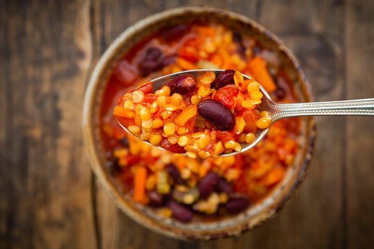 Spoon of vegan chili with red lentils, celery sticks, kidney beans, tomatoes and&Ocirc;&oslash;&Omega;carrots