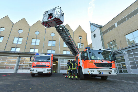 Two firefighters standing on yard at fire engine preparing for an operation