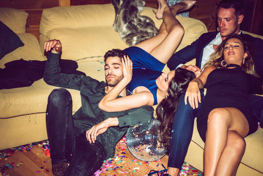 Tired male and female friends resting on sofa in party