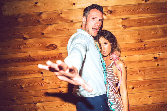 Young man showing stop gesture while embracing woman against wall in party