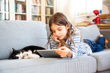 Portrait of girl lying on couch using digital tablet