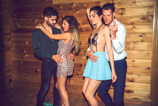 Young couples dancing sensually against wall in party