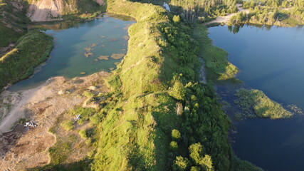 Naklejka premium Flooded and overgrown sand quarry. Lush green summer landscape for outdoors vacation, hiking, camping or tourism. Volokolamsk district of Moscow region. Sychevo beach, Russia