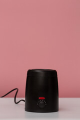 a device for heating wax on a pink wall background