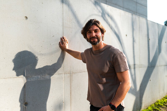 Mid adult man standing by wall while commuting in city