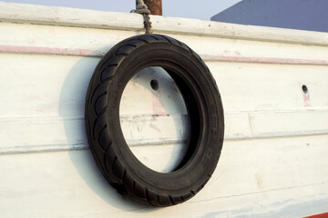 Side Of An Old Boat With Hanging Tire