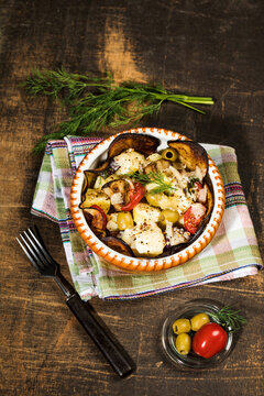 Casserole with aubergines, tomatoes, potatoes and green olives garnished with dill