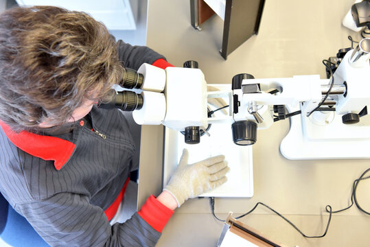 Woman using a microscope for the quality control in the manufacturing of ceramic circuit boards for the electronics industry
