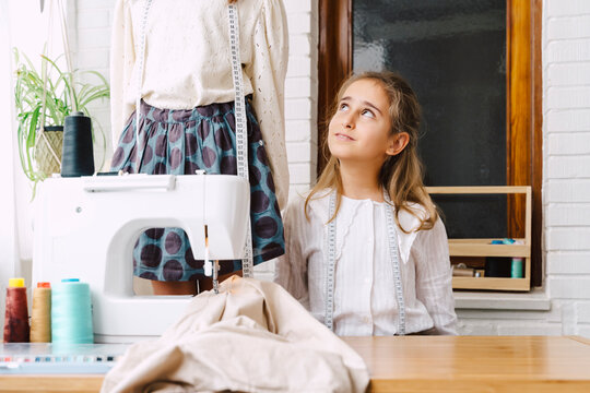 Girl looking up at sister with tape measure at home