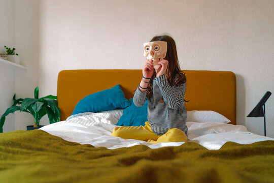Girl playing with toothless skull sitting on bed at home