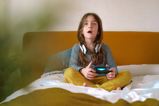 Girl playing video game sitting on bed