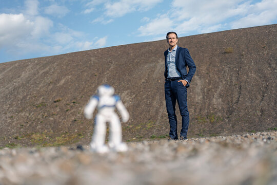 Businessman and miniature robot on a disused mine tip