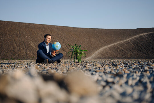 Mature businessman holding a globe on a disused mine tip