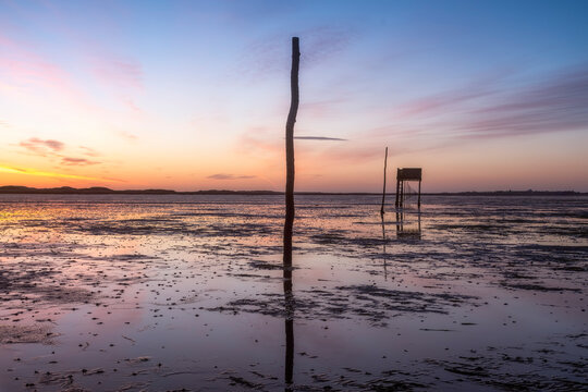 United Kingdom, England, Northumberland, posts marking the pilgrims' way crossing to Lindisfarne with emergency refuge, sunrise