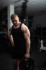 Fototapeta na wymiar Portrait of a handsome man in gym. Coach, athlete, bodybuilder, muscular sexy body, darkness.