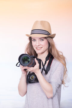 Portrait of smiling young woman comparing two different cameras