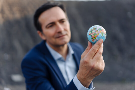 Mature businessman holding a globe on a disused mine tip