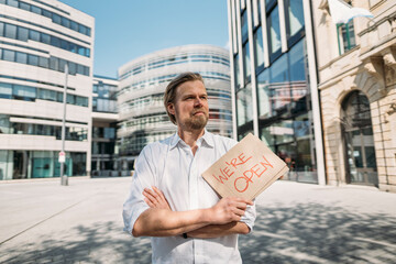 Shopkeeper holding cardboard with opening announcement in the city