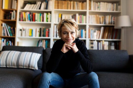 Portrait Of Smiling Mature Woman Sitting On Couch At Home